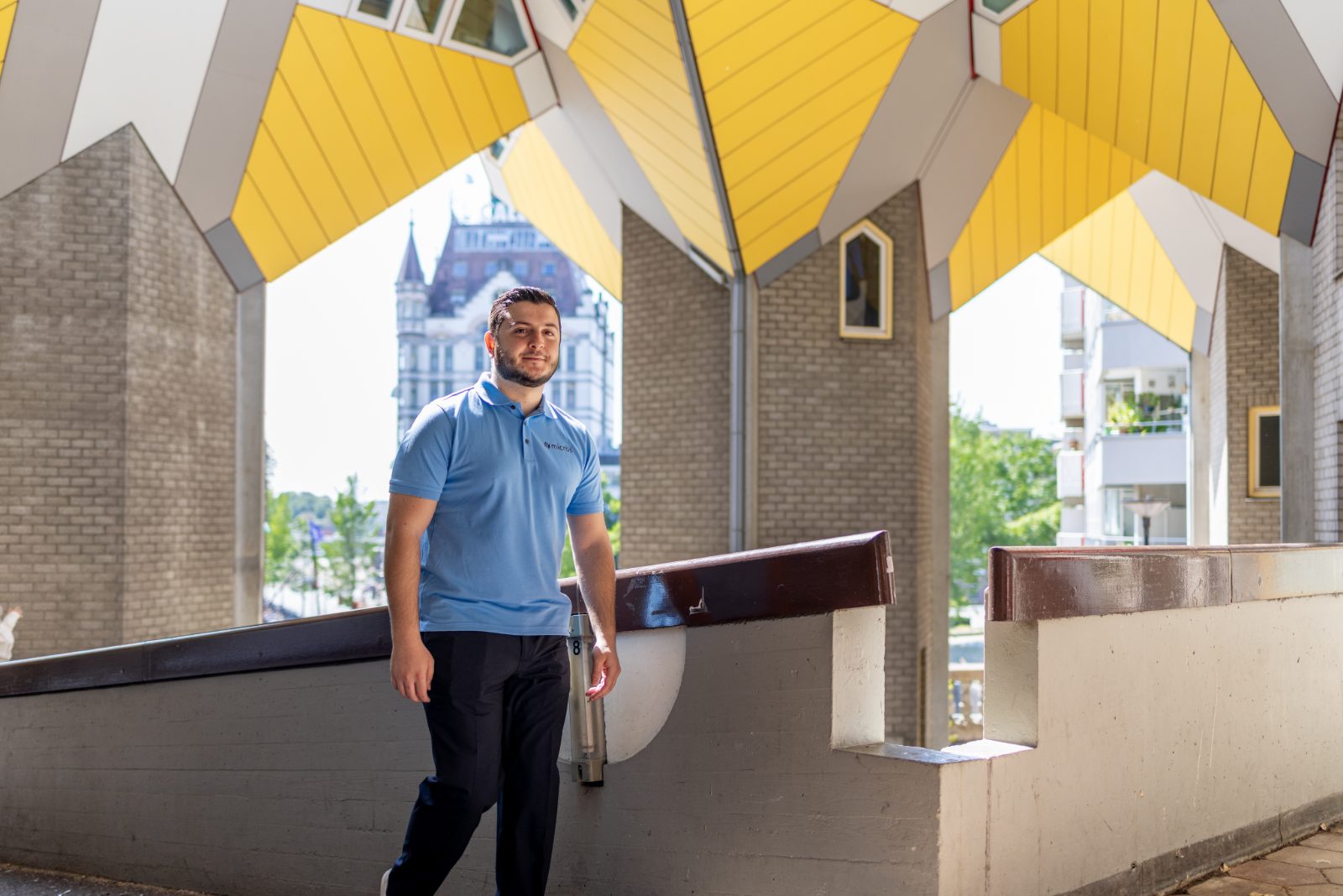 Micros-medewerker loopt met een drinkfles door de galerij van de Kubuswoningen in Rotterdam.