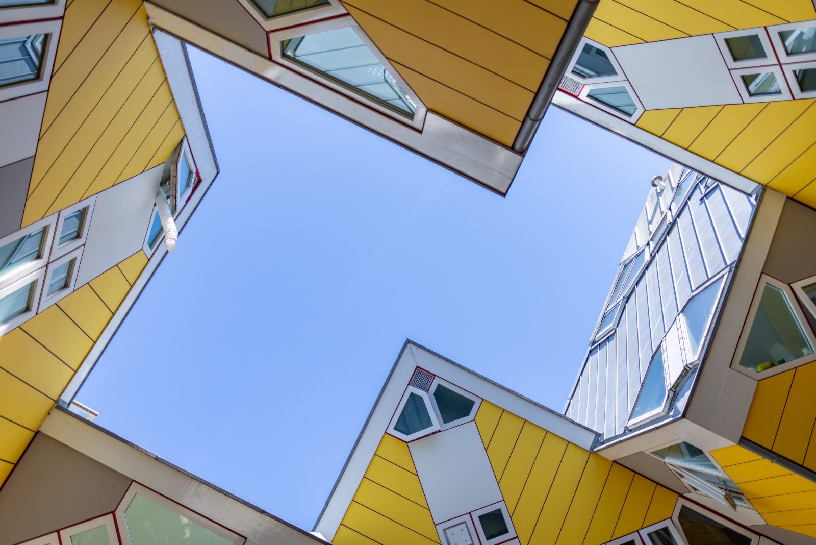 Kruisvormig blauw luchtvlak omringd door de gele Kubuswoningen in Rotterdam.