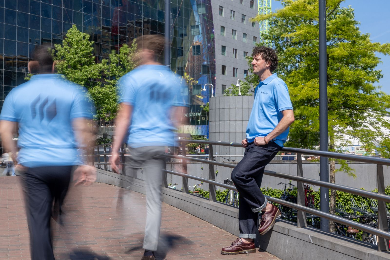 Micros-medewerker leunt tegen de reling terwijl collega's langslopen bij de Markthal in Rotterdam.