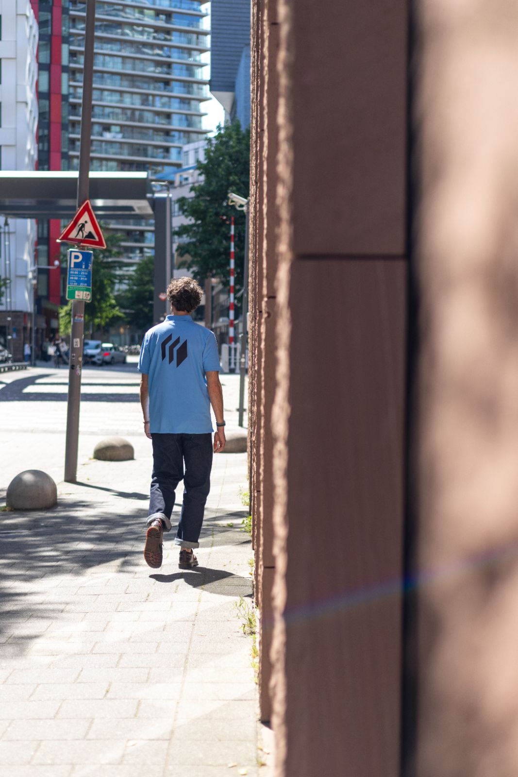 Micros-medewerker loopt weg over de stoep in de Rotterdamse binnenstad met logo op de rug.